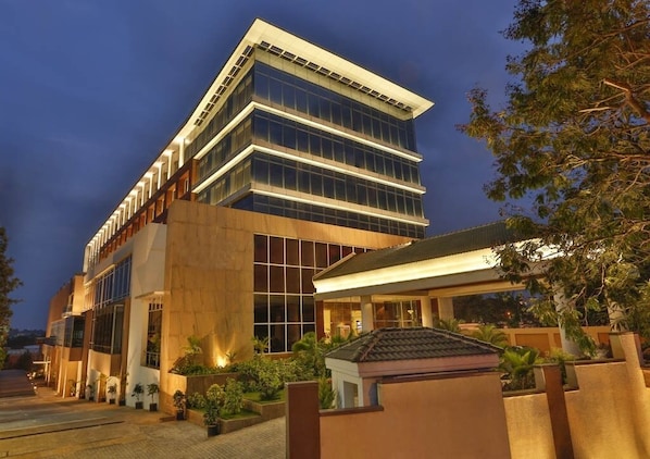 A modern hotel with a multi-story structure, large windows, and a well-lit entrance.