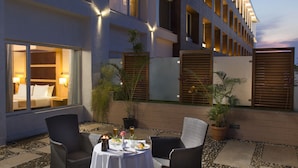 A hotel courtyard with outdoor seating, potted plants, and a well-lit building facade. -  Mysore County Retreat (Mysore)