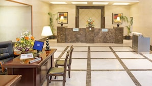 A reception area with a reception desk, two chairs, a computer, and a clock on the wall. -  Mysore County Retreat (Mysore)