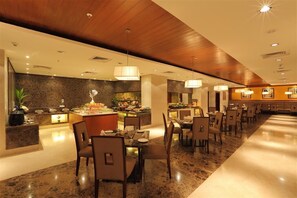 A modern hotel lobby with a central bar area, multiple dining tables, and a polished marble floor.