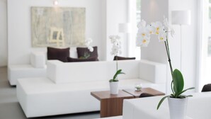 Een moderne woonkamer met een witte bank, een bijzettafeltje en een potorkidee.