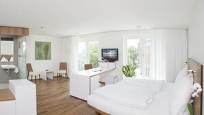Een moderne hotelkamer met een bed, een bureau, een televisie en uitzicht op het omliggende landschap.