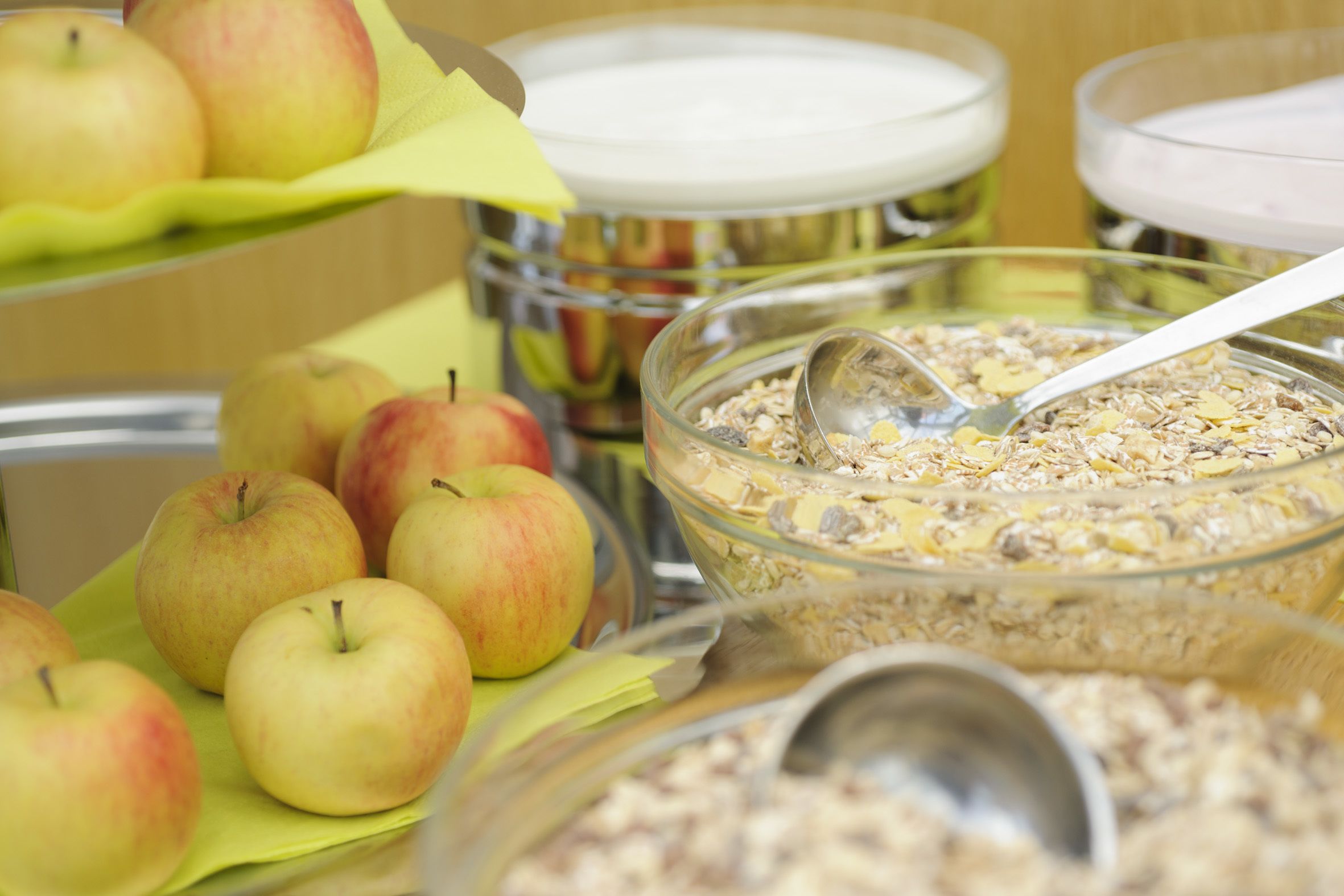 A breakfast buffet with apples and cereal bowls.