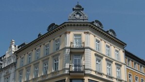 A corner of a building with a clock tower, multiple windows, and a balcony. - Hotel Augustiner Tor (Konstanz)