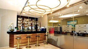 A bar area with a wooden counter, three gold bar stools, and a glass display case with bottles and glasses. - Sorriso Hotel (Istanbul)