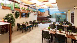 An outdoor dining area with multiple tables and chairs, potted plants, and a view of the sea. - Sorriso Hotel (Istanbul)