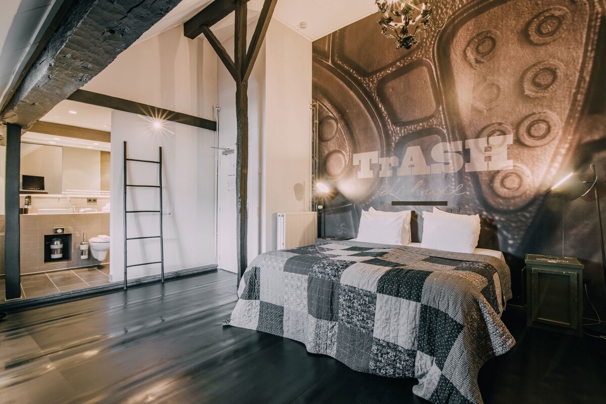 Un dormitorio con una cama grande, techo de madera, radiador y pared con diseño texturizado.