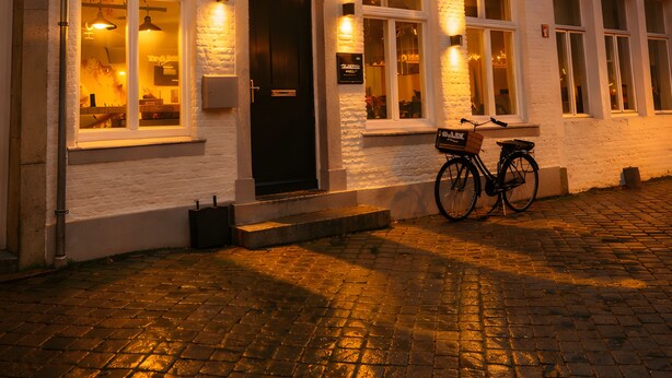 A white building with multiple windows and a bicycle parked in front. - Trash Deluxe (Maastricht)