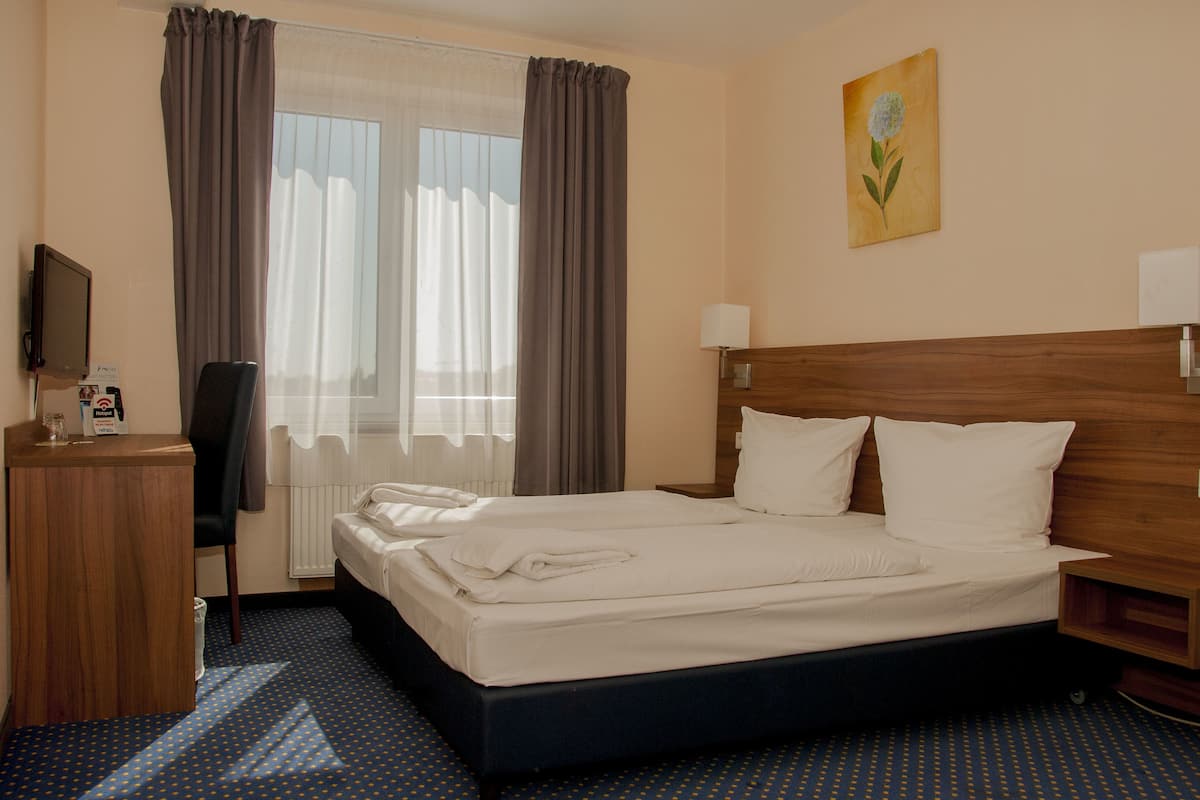 Une chambre d’hôtel avec un lit, un bureau, une chaise, une télévision et un tableau au mur.