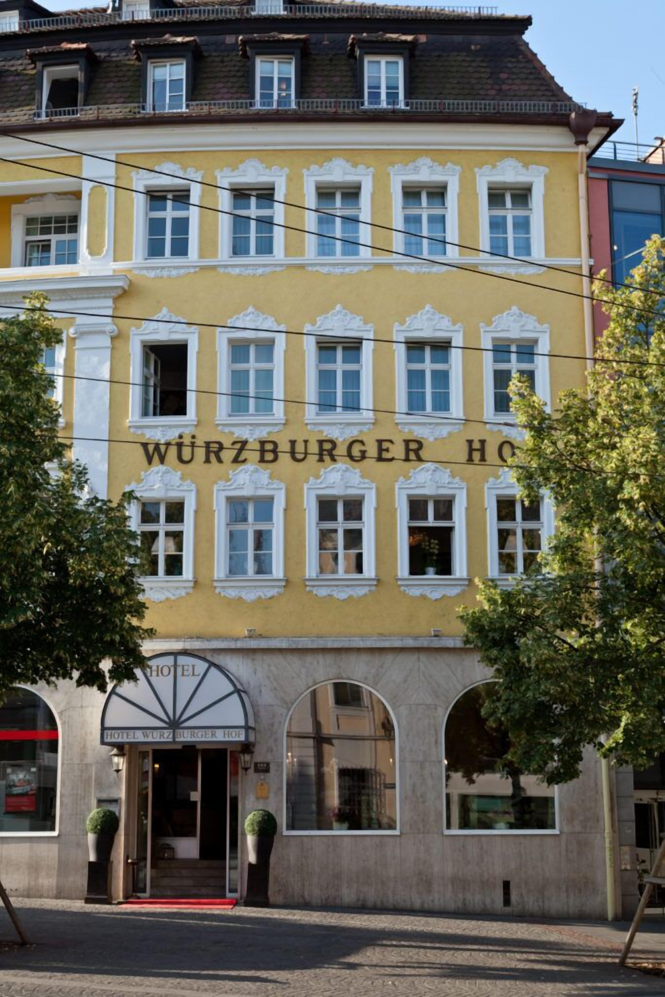 A yellow building with the sign "WURZBURGER HOTEL" and a red carpet entrance.