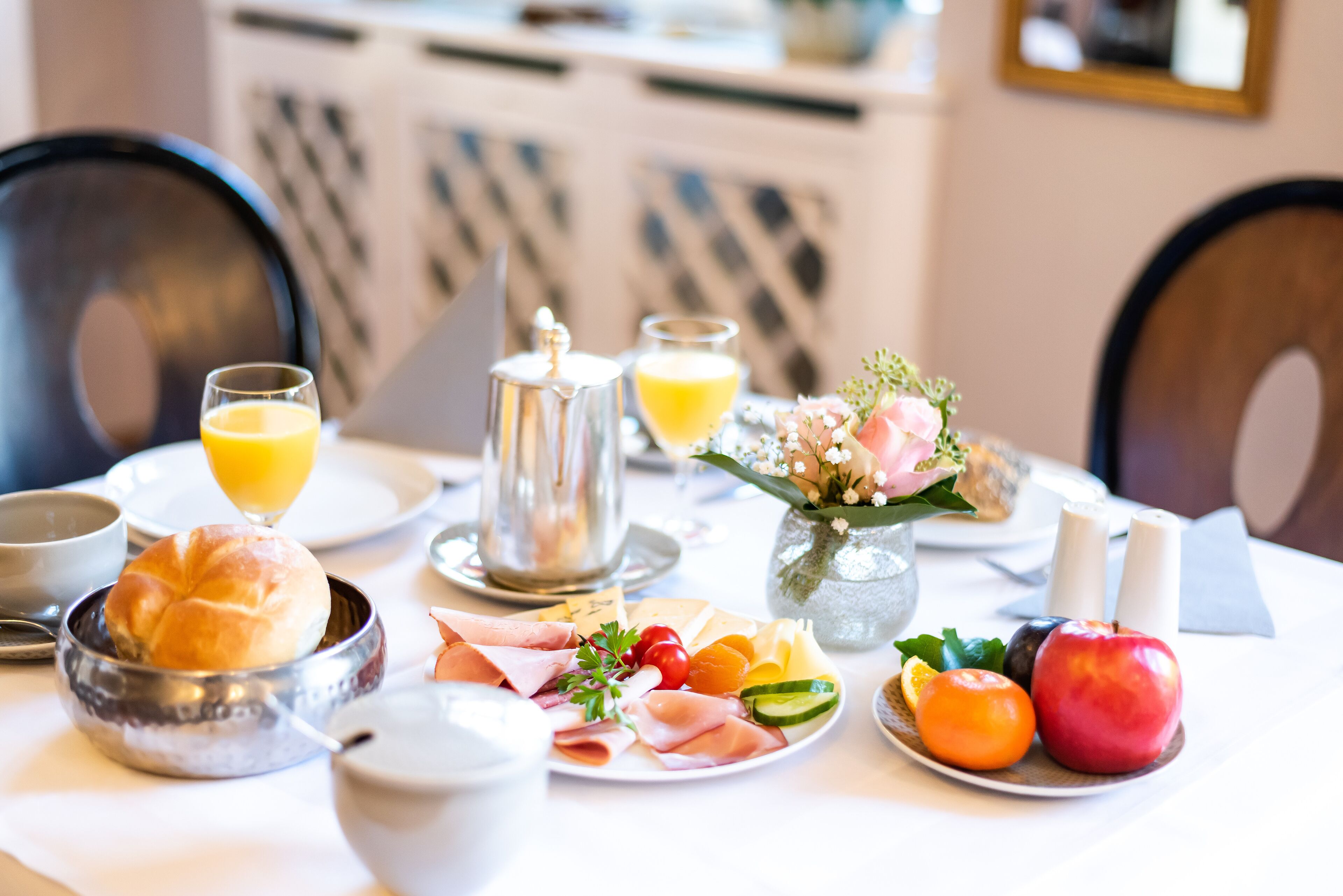 A breakfast setting with a variety of food items, including meats, fruits, and a beverage.