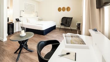 Un dormitorio moderno con una cama, un escritorio, una silla y una mesita.