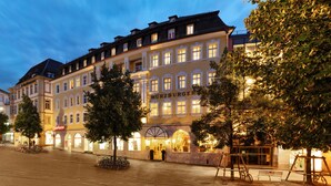 A historic hotel with a classic European facade, a central entrance, and a courtyard with trees and bicycles. - Hotel Würzburger Hof (Würzburg)