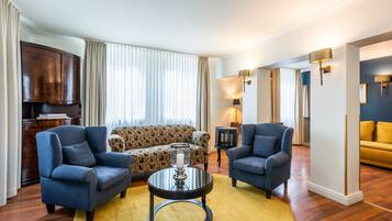 A living room with a sofa, two armchairs, a coffee table, and a TV.