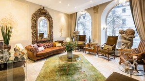 A spacious living room with a large mirror, leather sofa, and various decorative items. - Hotel Würzburger Hof (Würzburg)