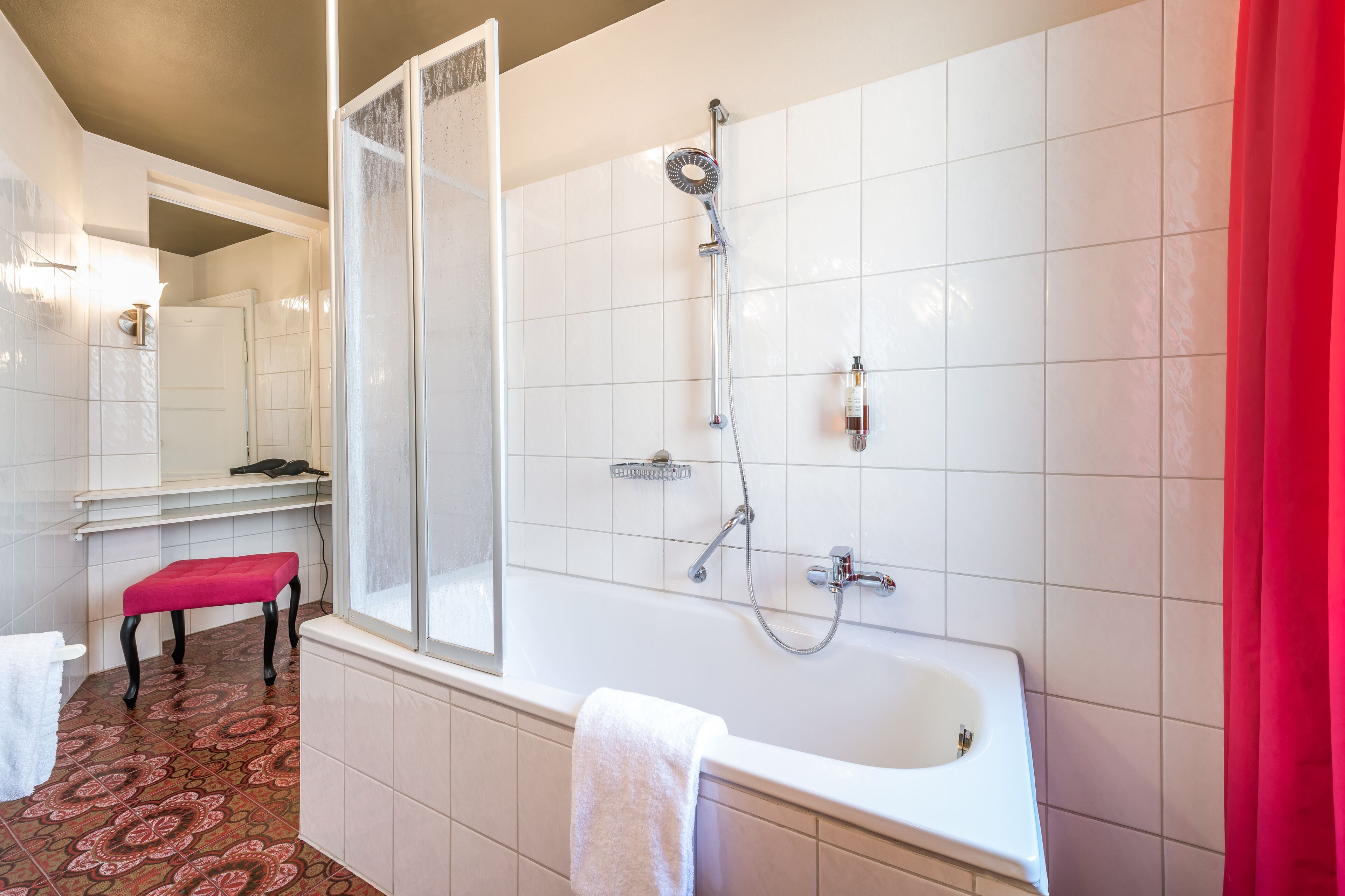 Ein Badezimmer mit einer Badewanne, einer Dusche, einer Sitzbank und einem Spiegel.