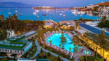 Una piscina al aire libre, sombrillas, sillones reclinables de piscina