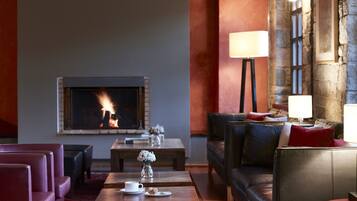A cozy living room with a fireplace, leather sofas, a coffee table, and a lamp.