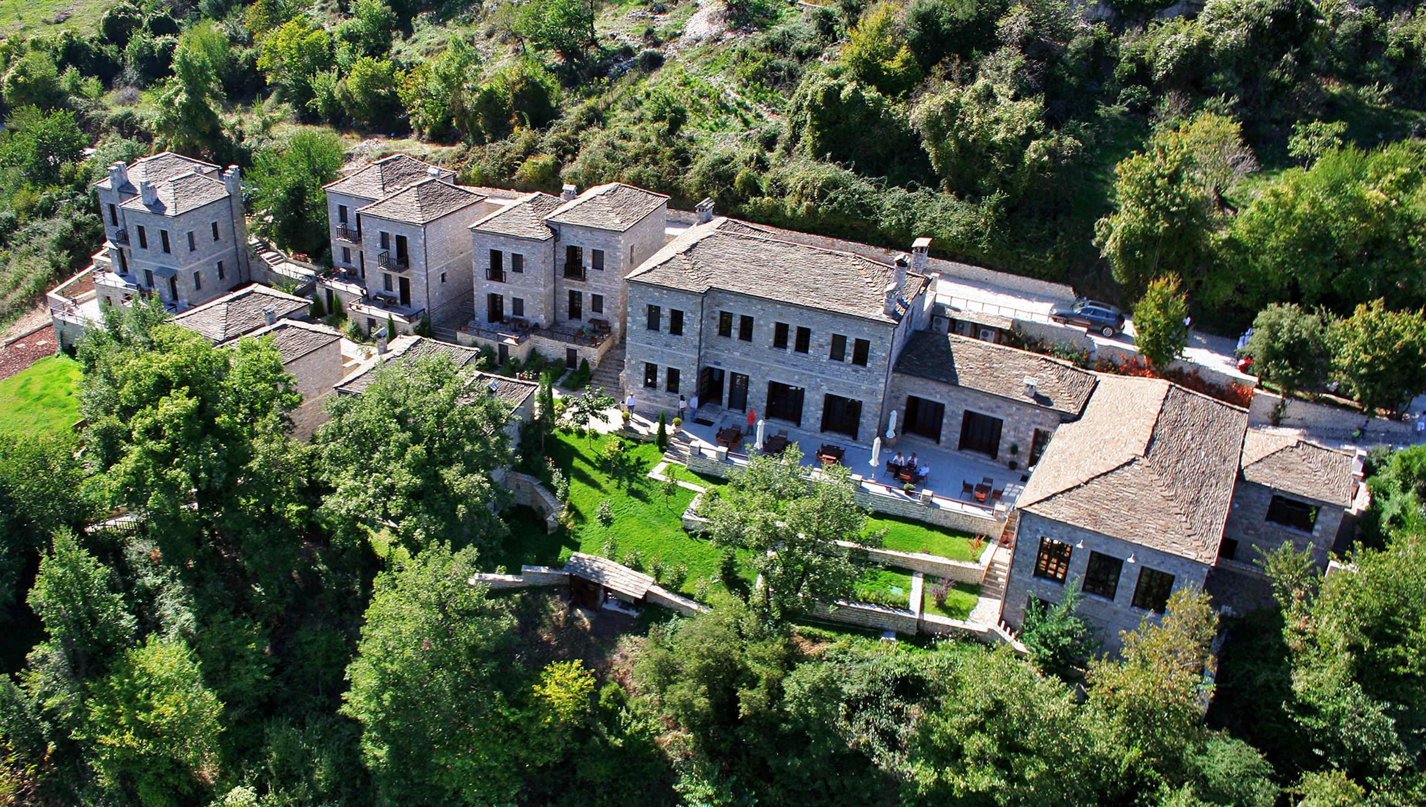 A large, multi-story stone building with a courtyard, surrounded by lush greenery.