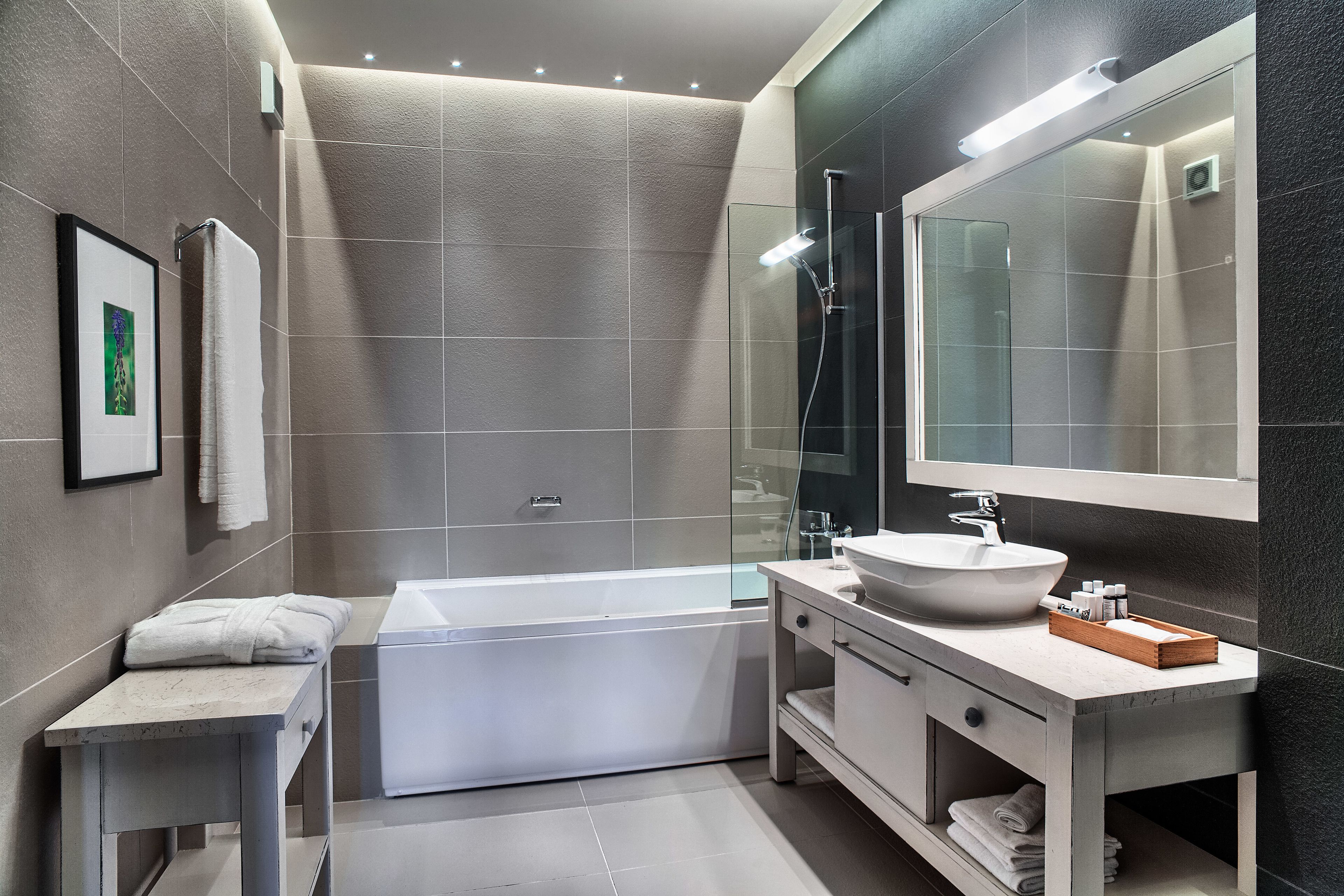 A modern bathroom with a bathtub, a large mirror, and a vanity with a sink.