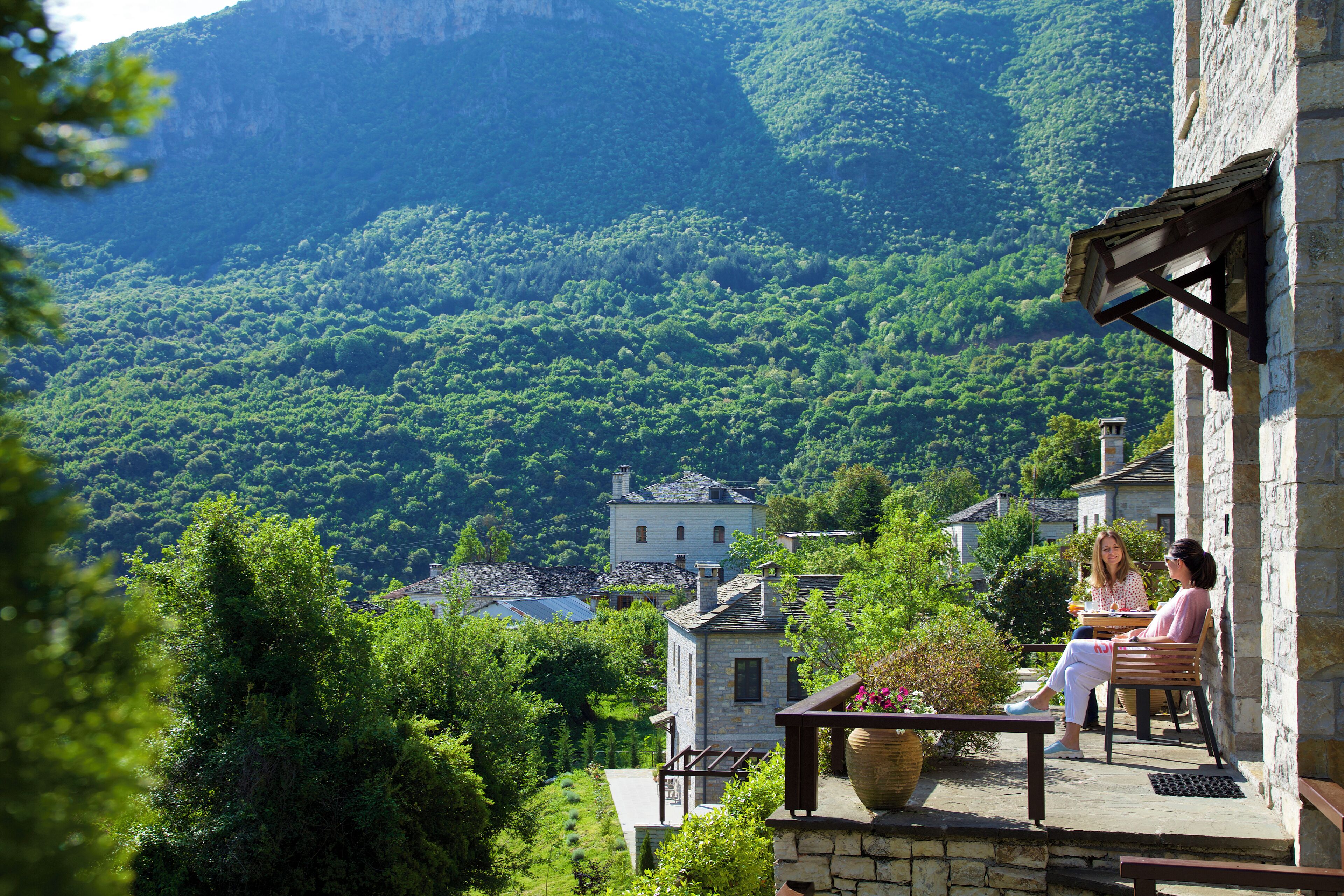 A stone building with a balcony overlooking a lush green valley.