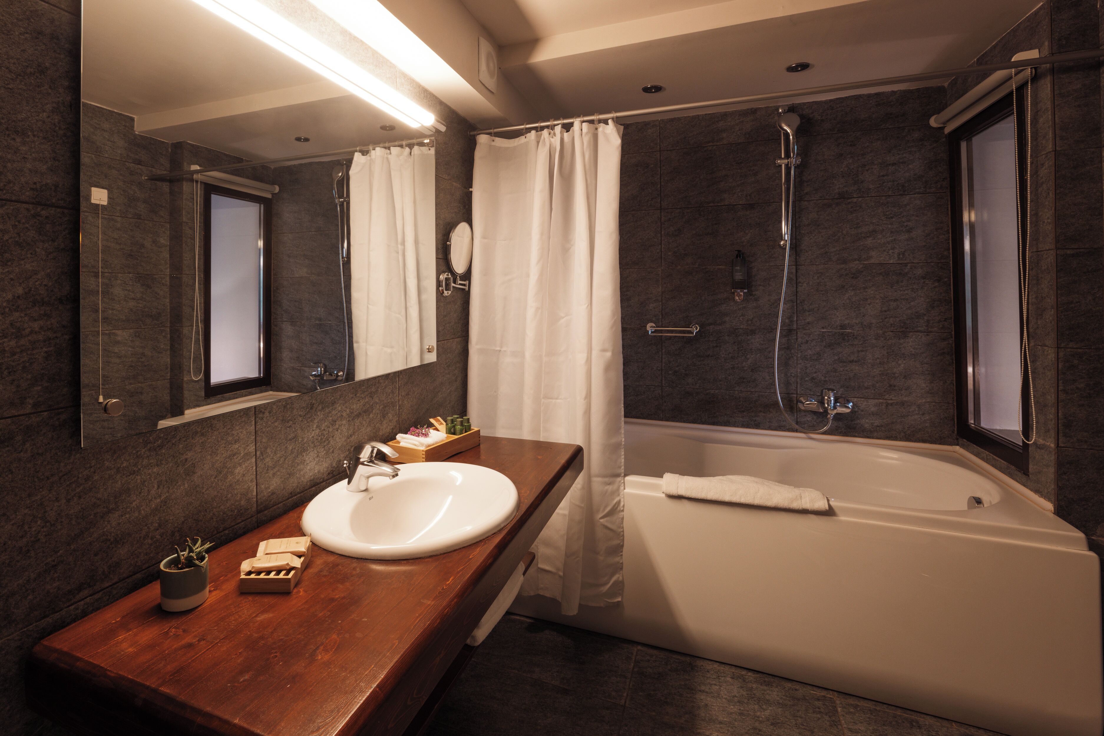 A modern bathroom with a wooden vanity, white sink, and a freestanding bathtub.
