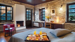 Una habitación acogedora con chimenea, paredes de piedra, cama, comedor y vistas al exterior.