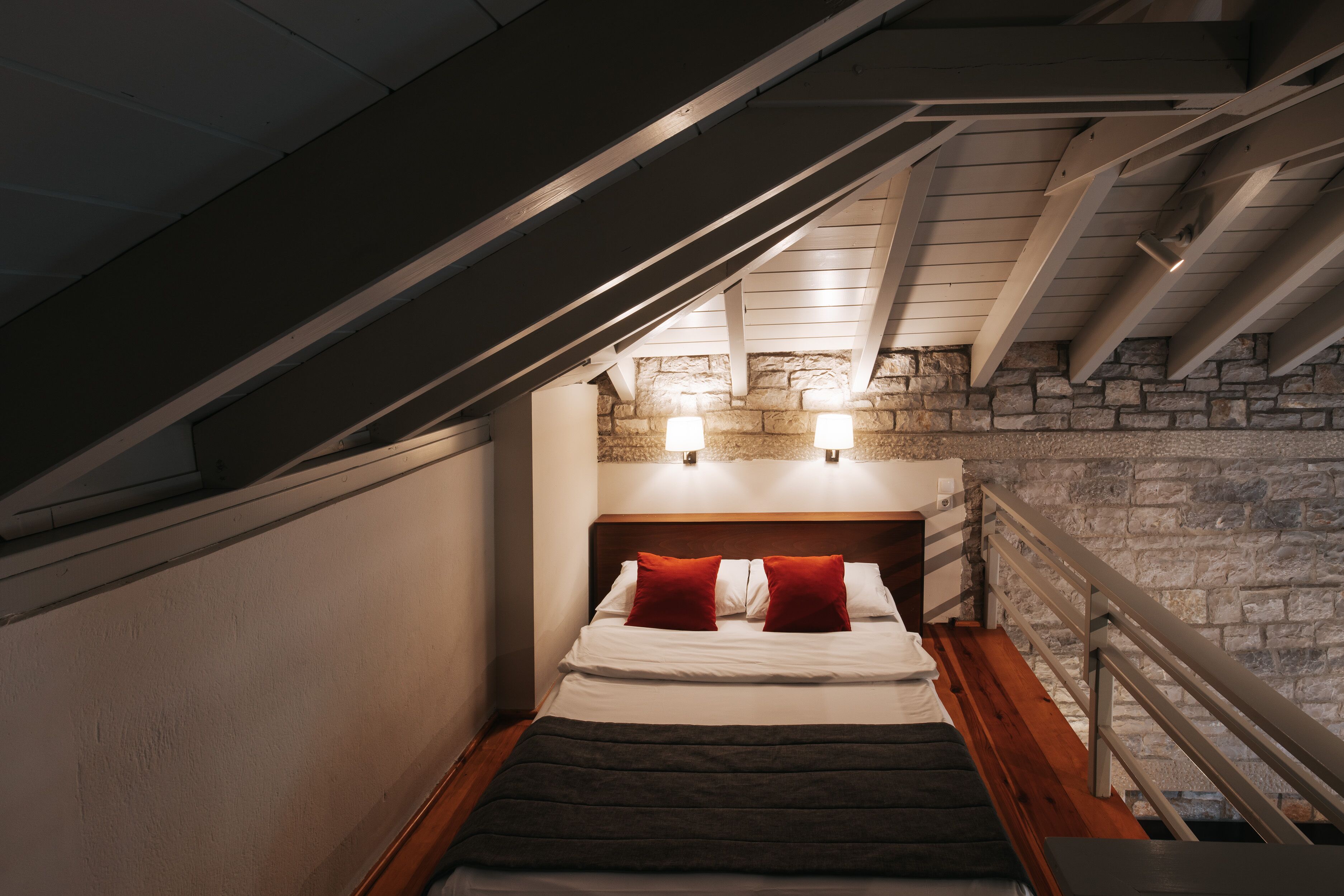 Un dormitorio con pared de piedra, cabecera de madera y una escalera.