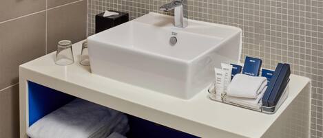 Un baño con un lavabo blanco, un espejo y artículos de aseo en la encimera.