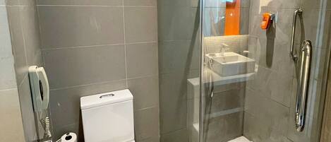A modern bathroom with a glass-enclosed shower, a toilet, and a sink.