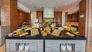 A buffet setup with various food items and a chef present.