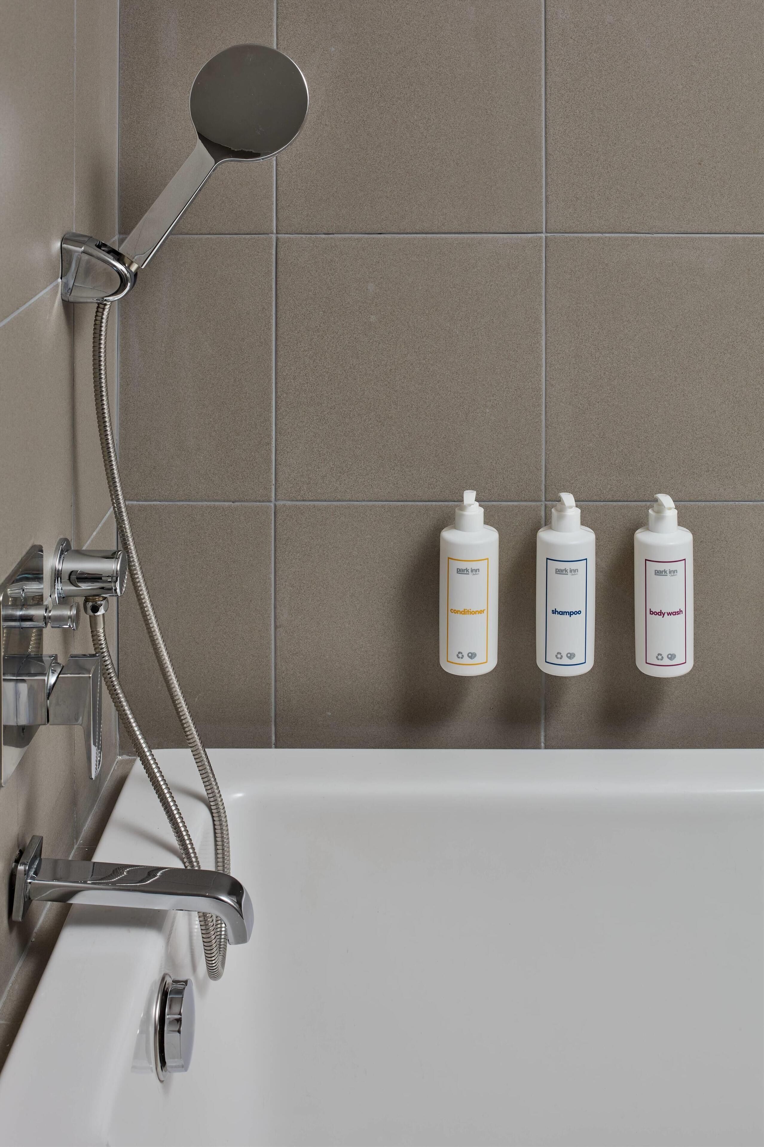 Un baño con ducha, bañera y tres artículos de tocador en la pared.