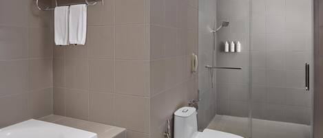 A modern bathroom with a bathtub, toilet, and glass-enclosed shower.