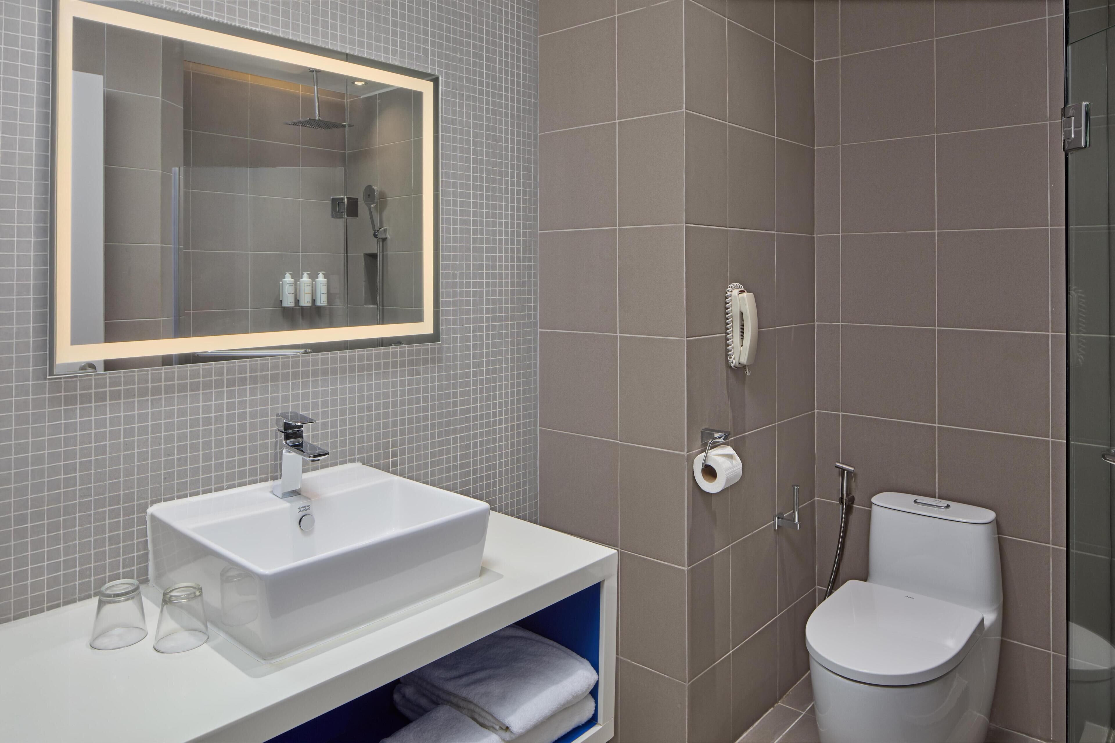 A bathroom with a white sink, mirror, and toilet.