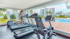 A gym with treadmills and a pool view.