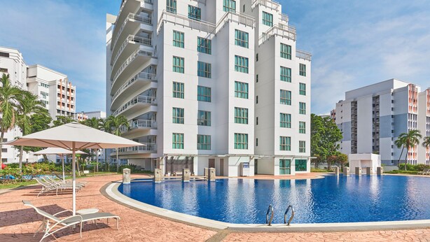 A modern hotel with a swimming pool, multiple balconies, and a well-maintained garden area.