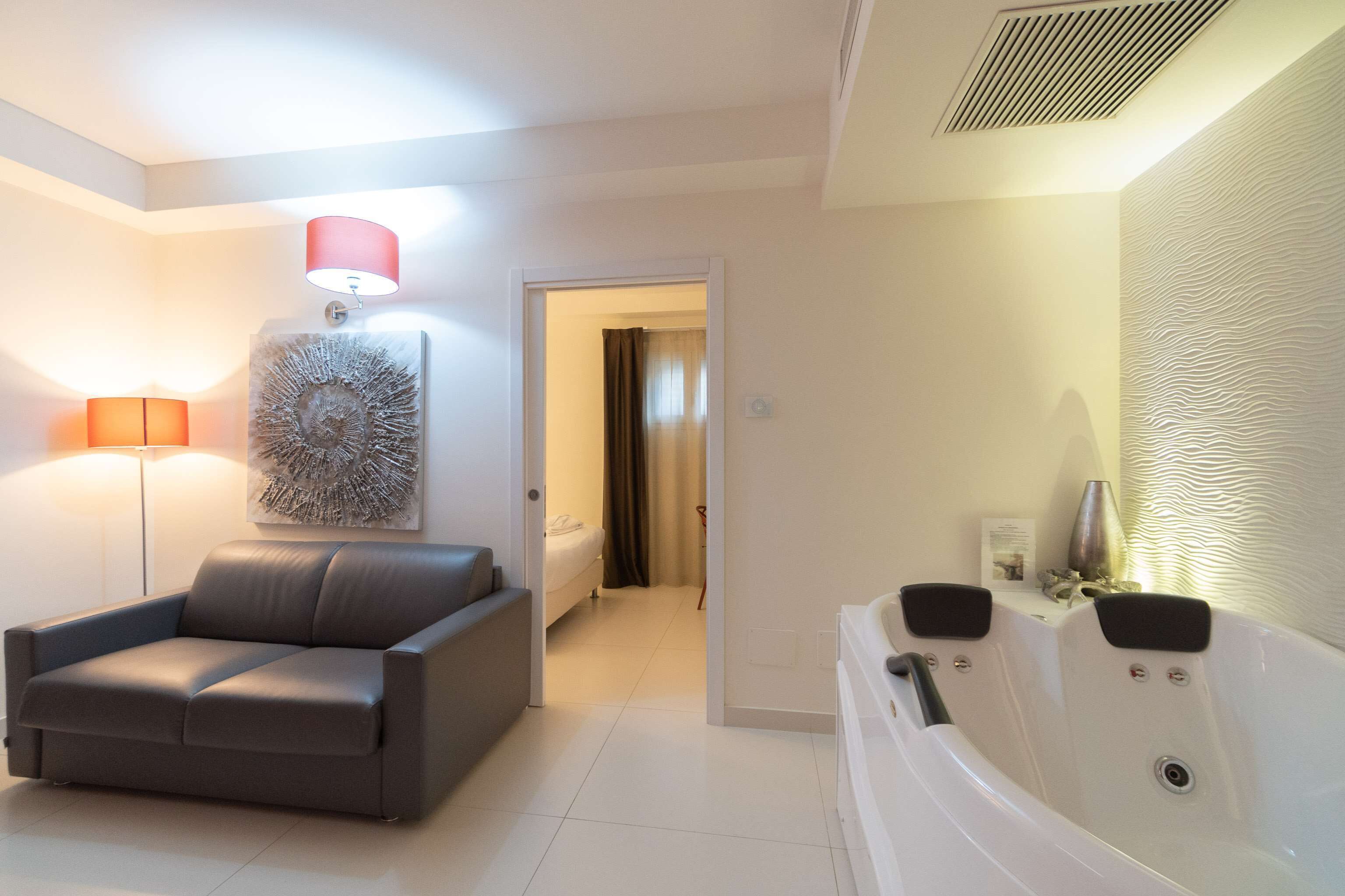 A modern bathroom with a bathtub, a sofa, and a floor lamp.