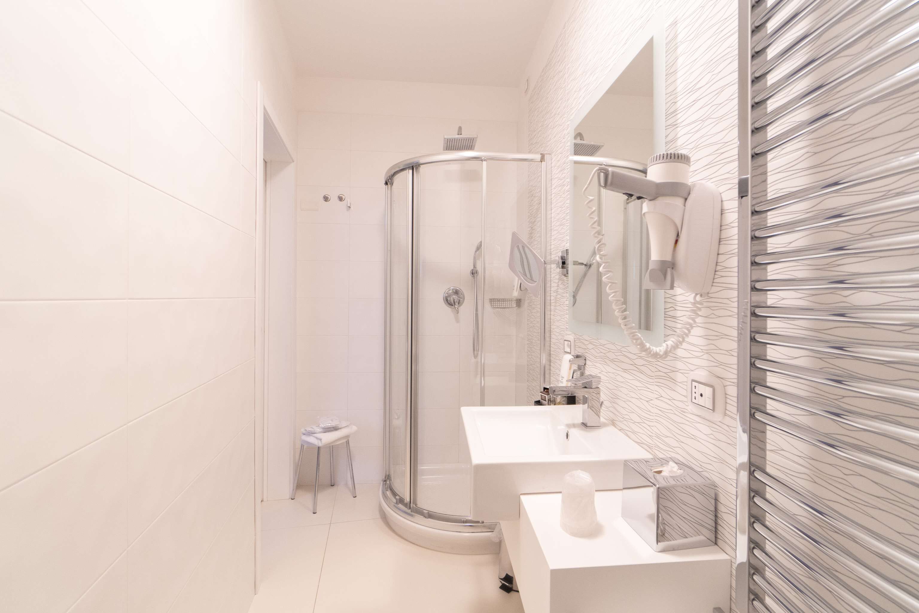 A modern bathroom with a glass-enclosed shower, a white sink, and a mirror above the sink.