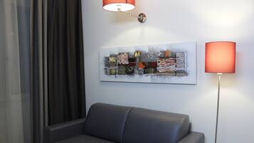 A modern living room with a grey sofa, a contemporary abstract painting, and two floor lamps.