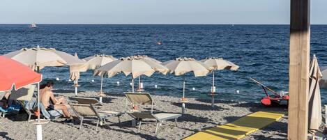 Una playa con hileras de sombrillas y sillas de descanso.