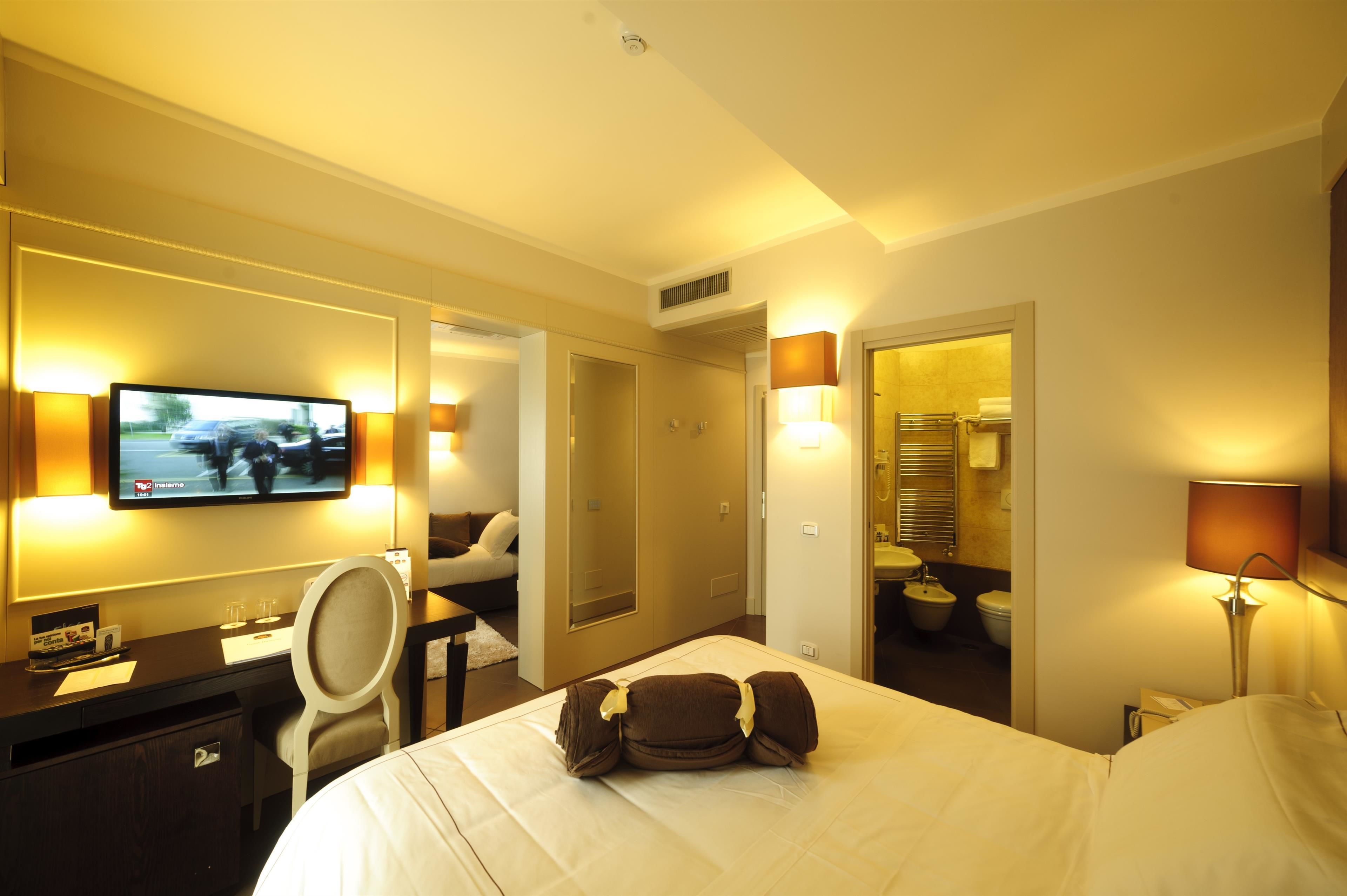 A hotel room with a bed, desk, chair, TV, and bathroom.
