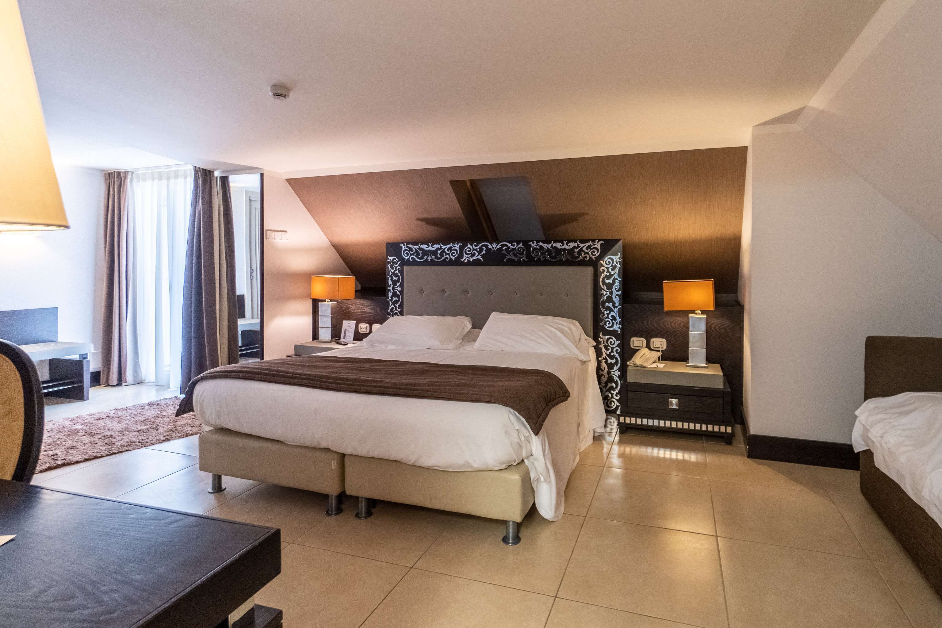 Ein Hotelzimmer mit einem großen Bett, Nachttischen mit Lampen, einem Schreibtisch und einem Stuhl.