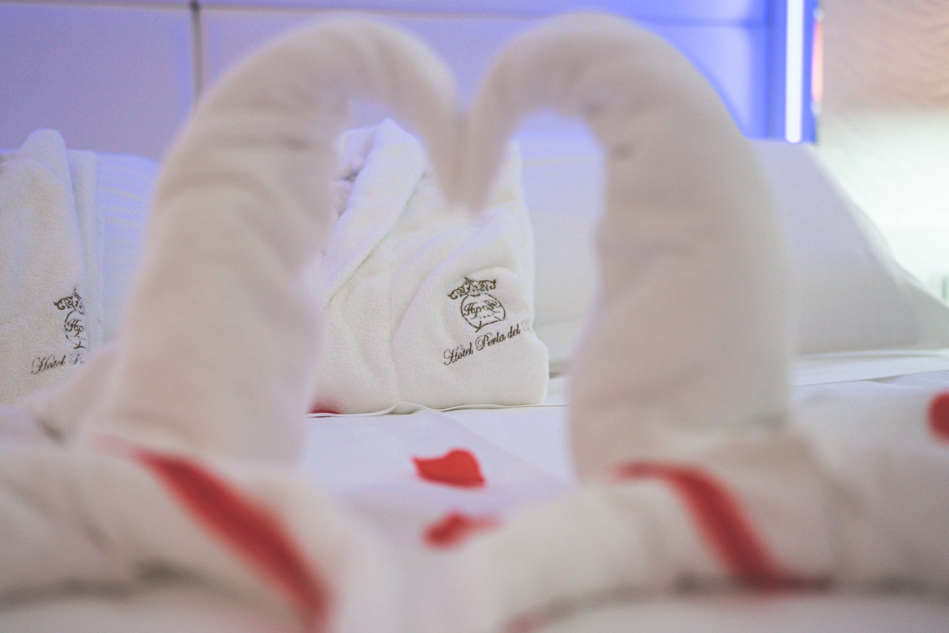 Una cama con toallas blancas y una decoración con forma de corazón.