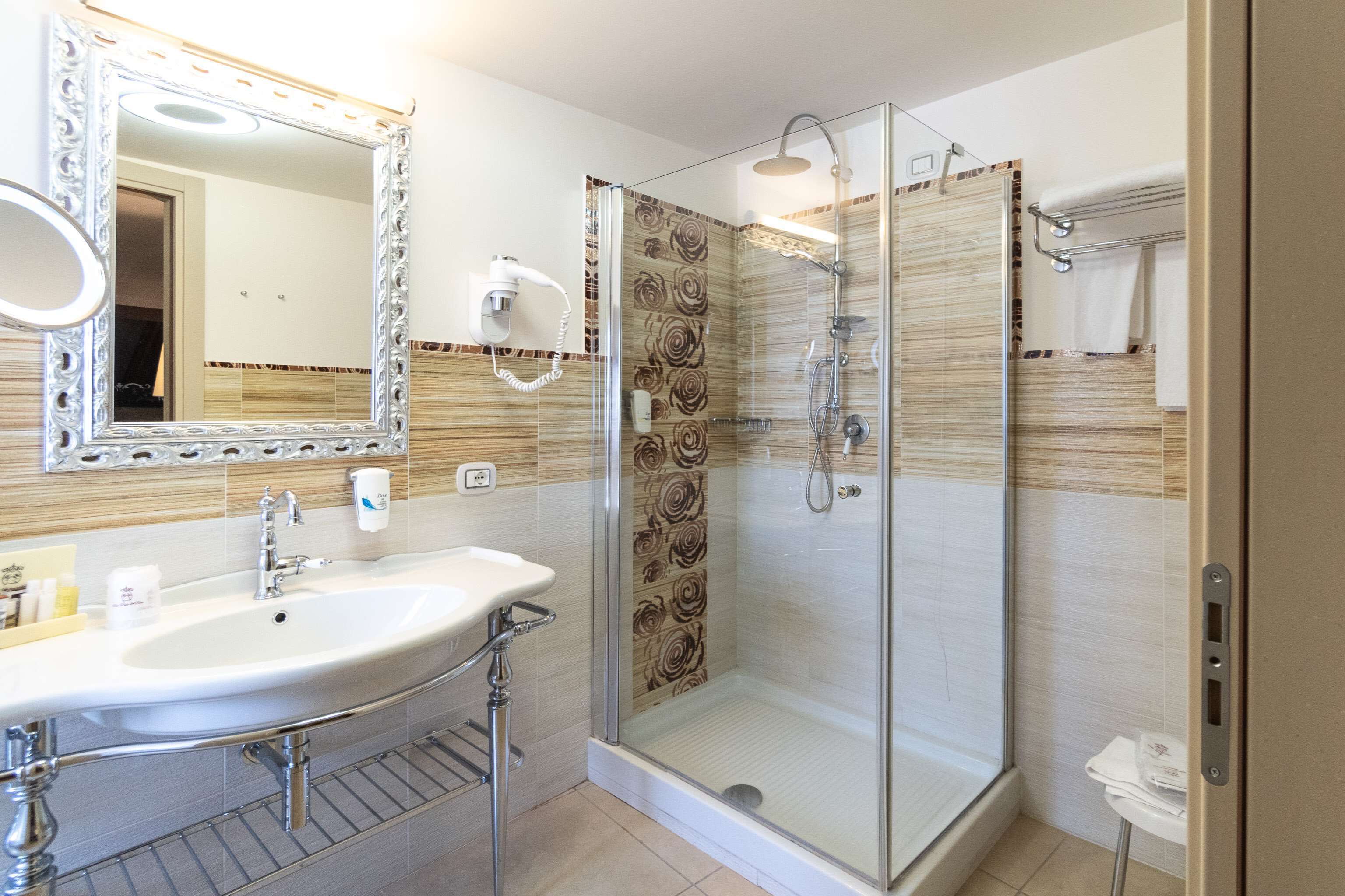 Un bagno con doccia vetro, uno specchio grande e un lavabo con mobile contenitore.