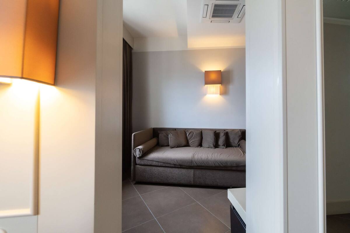A modern living room with a sofa, a wall-mounted lamp, and a tiled floor.