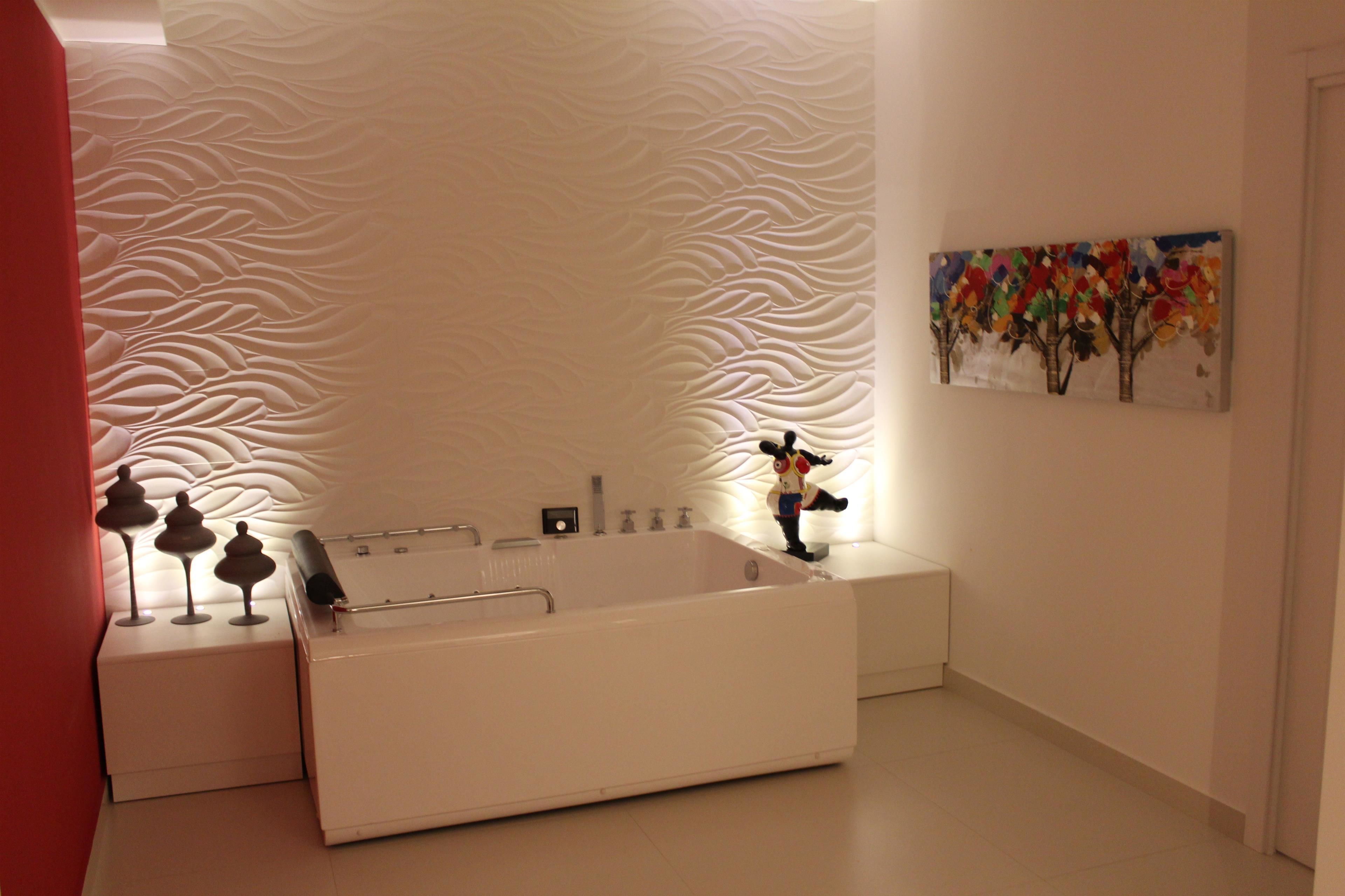 A modern bathroom with a freestanding bathtub, a wall-mounted sink, and a decorative wall panel.