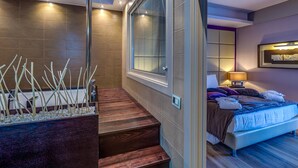 Un dormitorio moderno con una cama grande, una mesita de noche y un ventanal con persianas.