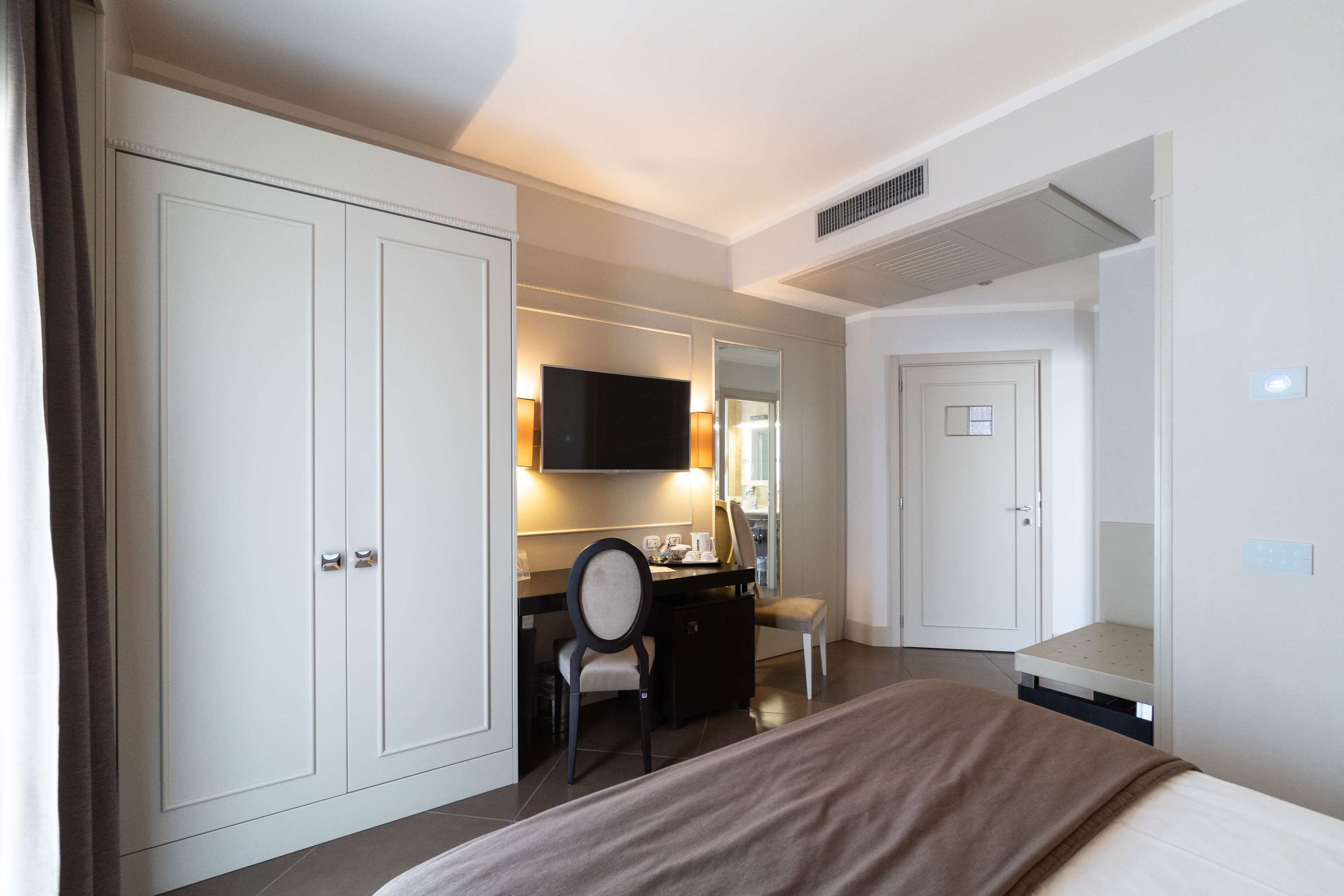 Une chambre d’hôtel comprenant un lit, un bureau, une chaise, une télévision et une armoire.