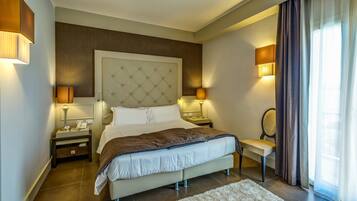 A modern hotel bedroom with a large bed, bedside lamps, a chair, and a view of the outdoors through curtains.