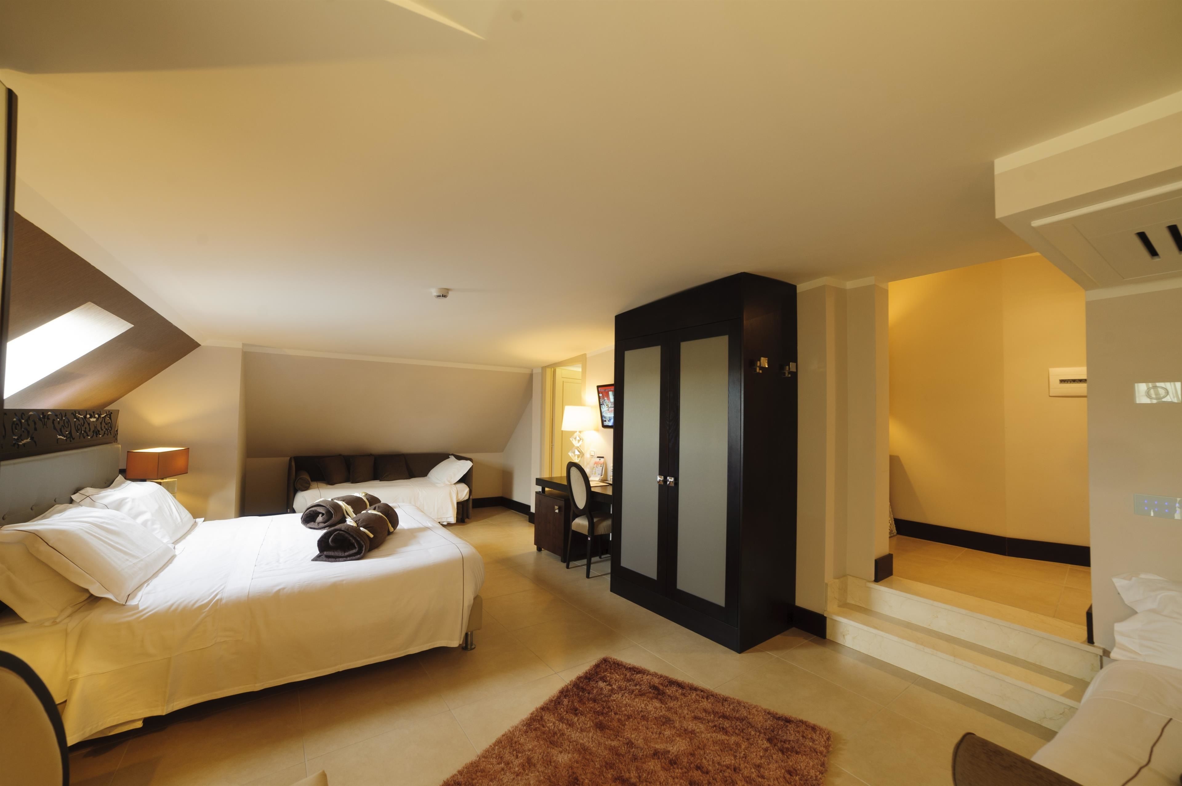 Ein Hotelzimmer mit Bett, Schreibtisch, Kleiderschrank und einer Treppe, die in eine andere Ebene führt.